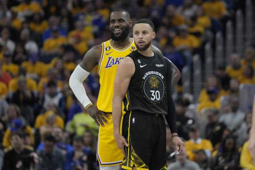 Lakers forward LeBron James stands behind Golden State Warriors guard Stephen Curry